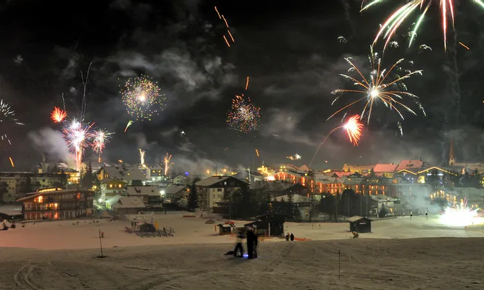 Colorful fireworks over snowy alpine village at night during winter celebration
